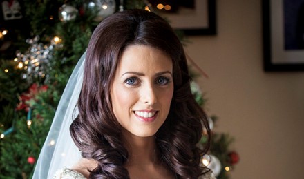 bride beside a christmass tree holding her wedding flowers bridal hair and make up done. beautiful jewelry posing for her photographer.