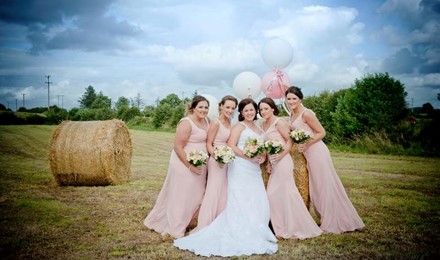 quirky wedding photo pink dress bales baloons flowers field makeup artist mayo sligo donegal blue sky clouds green trees  background wedding morning on the way to the church. 